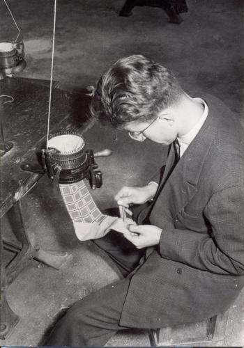 Un alumne fent un mitjó amb una màquina circular de petit diàmetre manual. Gener 1955