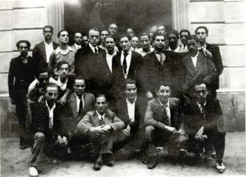 Grup d’alumnes davant la porta d’entrada de l’Escola de Teixits de Punt. El quart per l’esquerra, dempeus, el director, Paul-Émile Muller, c.1931-1935. Autoria desconeguda. Fons: Diputació de Barcelona (CAT AGDB R. 2742)